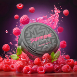A can of Supreme raspberry-flavoured nicotine pouches, surrounded by fresh raspberries and a splash of juice